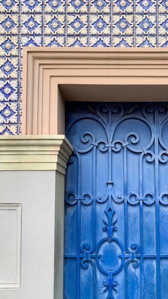 a photo of a beautifully ornate grated blue door and blue and white tile building in Porto, Portugal