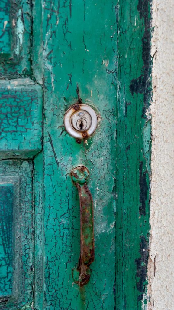 close up photo of green distressed wooden door in Ericeria, Portugal