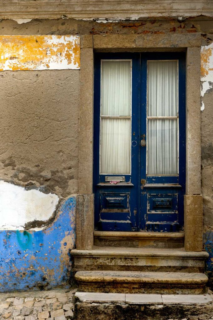 photo of dark blue distressed door and concrete facade of house in Ericeria, Portugal