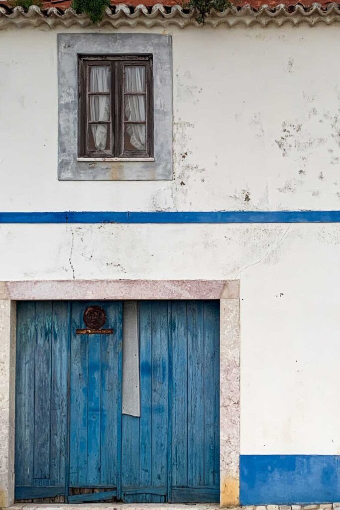 a photo of a White House with blue double wide door in Ericeria, Portugal