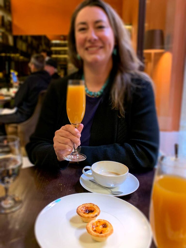 a woman enjoying Pastéis de Nata and a mimosa for brunch at Vignette Collection Casa da Companhia in Porto, Portugal